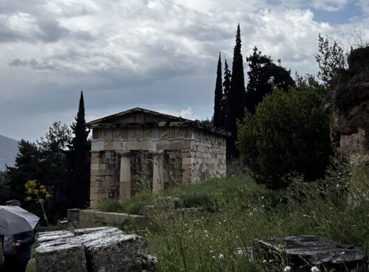 a greek temple in Delphi with a cloudy background