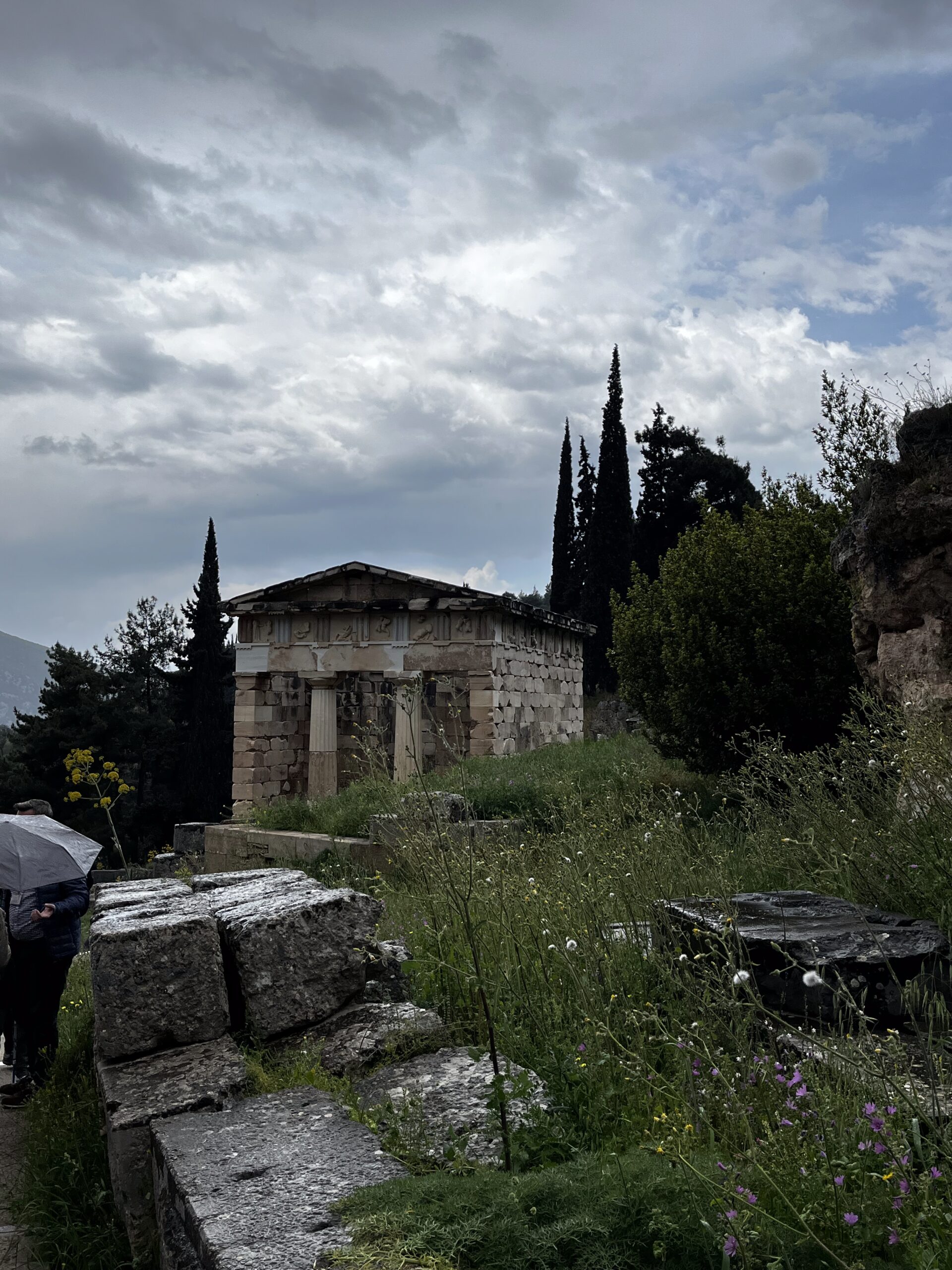 a greek temple in Delphi with a cloudy background