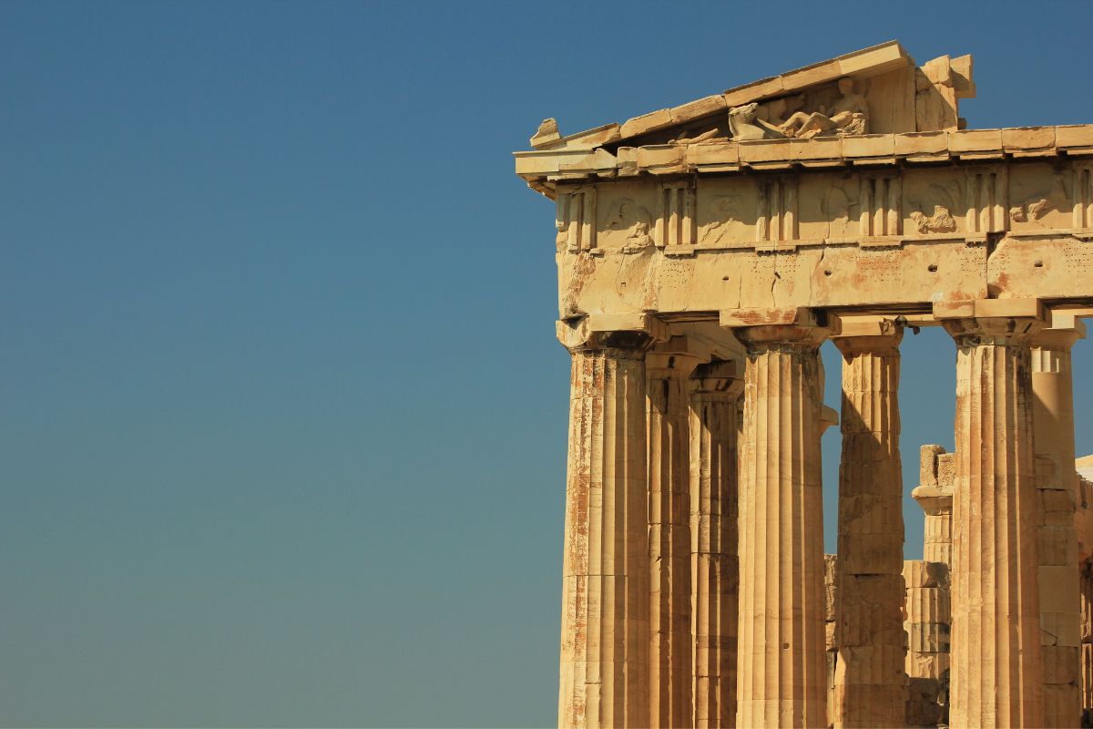 A close-up view of the Parthenon in Athens, showcasing its ancient columns and architectural details against a clear blue sky.